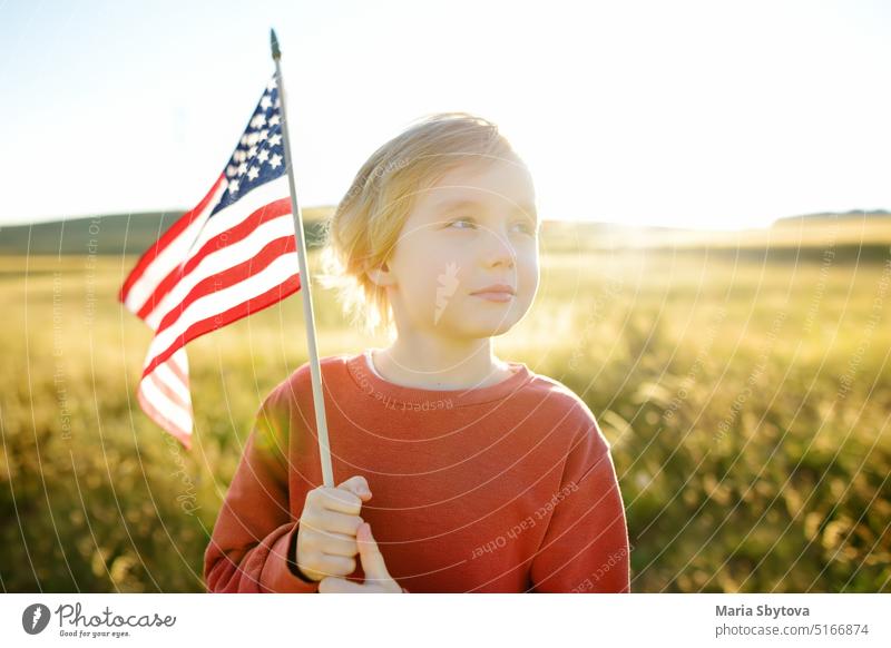 Proud little american boy holding his country flag usa proud child caucasian white july 4 cute kid sunset waving summer symbol grass baby landscape happy stars