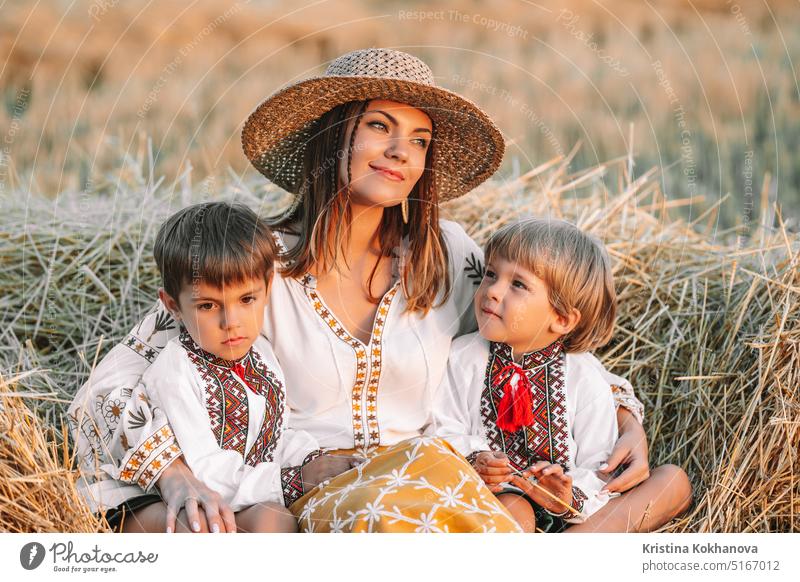 Beautiful ukrainian family - woman sons in vyshyvanka shirts on hay, countryside active activity boy boys brothers cheerful child childhood children