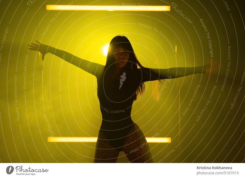 Sexy woman dancing on yellow led lamps hazy background. She looks seductively. adult alluring attractive backlit beautiful beauty body caucasian clubbing dance