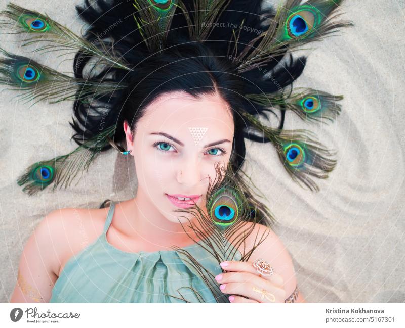 Portrait of stylish woman on beach. flash tattoos on hands and peacock feather. beautiful beauty elegance face fashion female girl lips makeup model portrait
