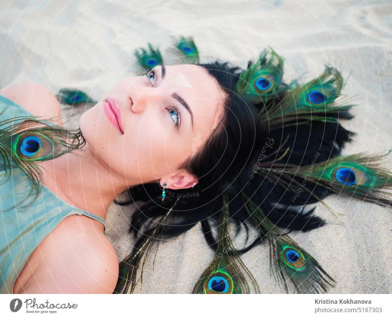 Portrait of stylish woman on beach. flash tattoos on hands and peacock feather. beautiful beauty elegance face fashion female girl lips makeup model portrait