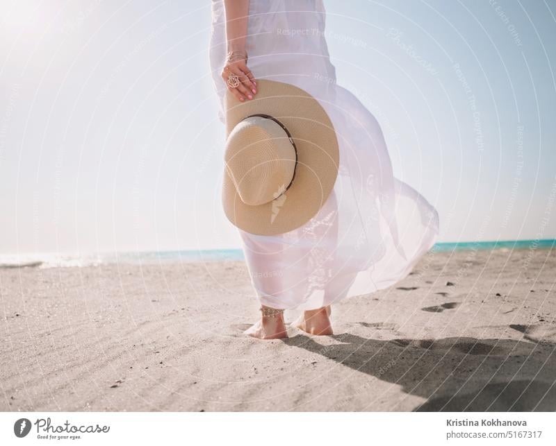 Beautiful girl holding hat on sea beach. Woman wearing in long white dress summer walking woman holiday nature ocean water vacation sand adult beautiful