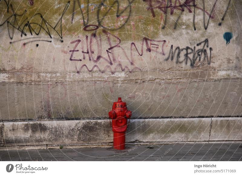A bright red water tap for the fire department in front of an old house wall painted with graffiti Graffiti Graffiti wall Fire department water dispenser amatur