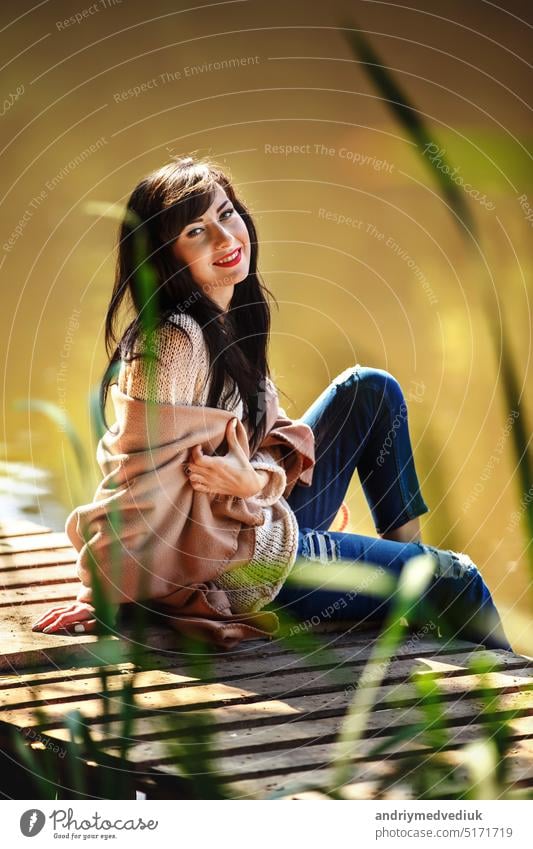 Beautiful girl with long brunette hair sitting on the bridge. nature black beautiful summer sky woman colorful calm board background forest autumn wood wind