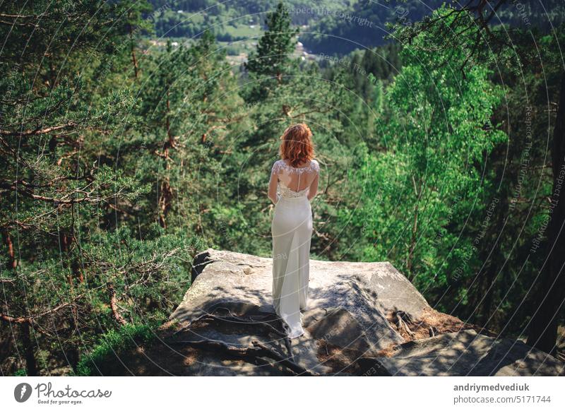 beautiful young redhead bride in the forest with a flower wreath on her head. woman in long white dress outdoors on a summer day. wedding day Bride forests