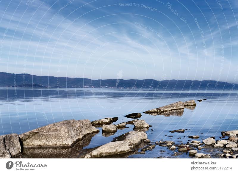 Rocks in the lake Trasimeno shore , Italy nature water landscape Trasimeno lake travel lake shore sky copy space blue view stone water reflections rocks outdoor