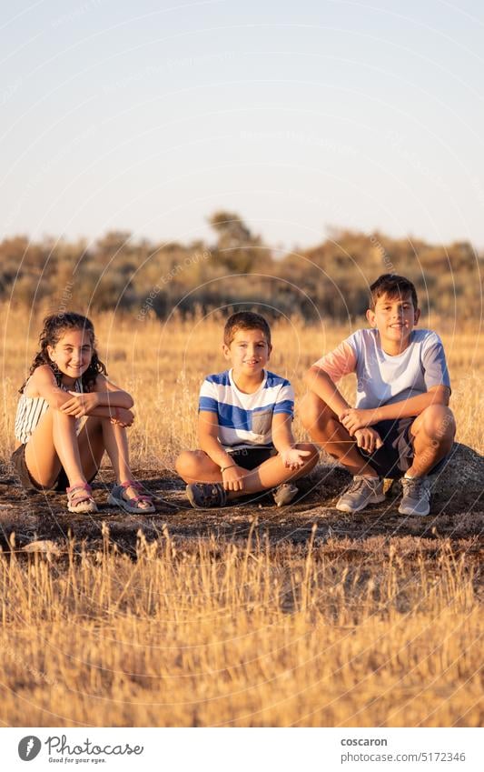 Three kids sitting  on a rock on their summer vacation active adventure blue boy camp child childhood climbing dry explore family field forest girl happiness