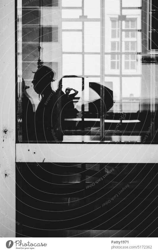 Human silhouettes in front of a geometric facade reflected in a glass pane Silhouette reflection man with hat Pane Shadow Mysterious Reflection Contrast