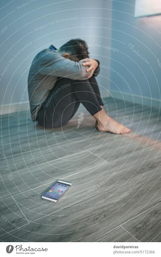 Man with problems sitting on the floor with mobile on the floor unrecognizable faceless man guy desperate cover mental disorder smartphone harassment internet