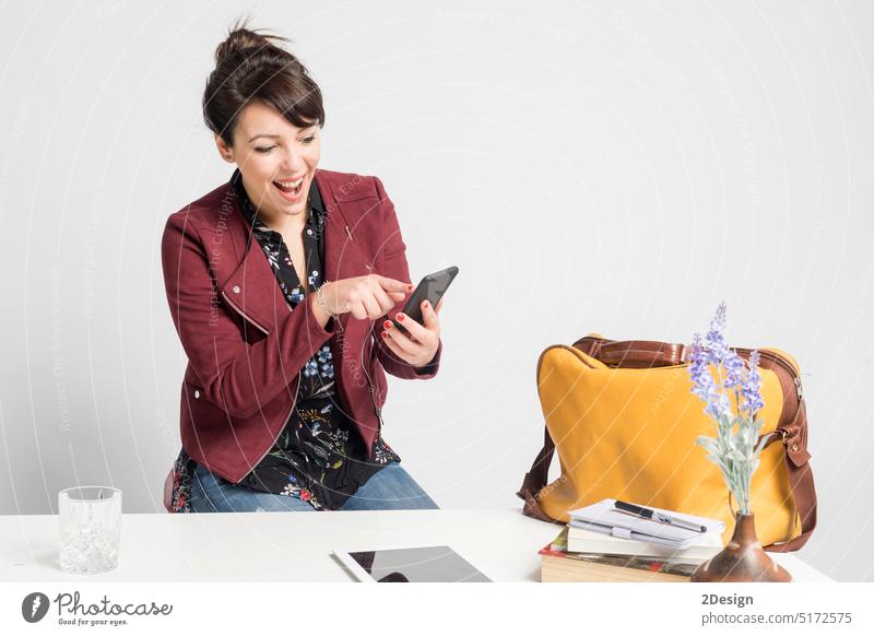 business woman using phone and tablet sitting on a desk at home workplace, person ponytail female technology online young girl happy mobile studio smartphone