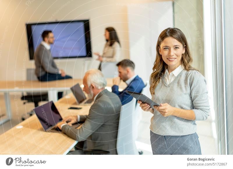 Young business woman at startup office with digital tablet in front of her colleagues as team leader adult attractive beautiful beauty businessperson