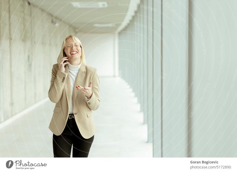 Businesswoman using mobile phone on modern office hallway adult beauty blonde business business person businesspeople businessperson businesswoman call