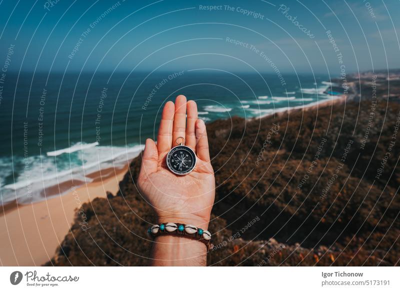 POV man hand with compass. Symbolling adventure-seeking concept against sea and waves in coastline in background beach moody discovery pov point of view