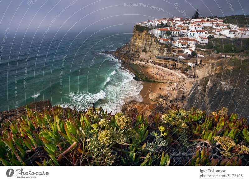 Dreamy view of the picturesque village Azenhas do Mar in sunset light with chalk houses on the edge of a cliff and beach below. Sintra Landmark, Portugal, Europe