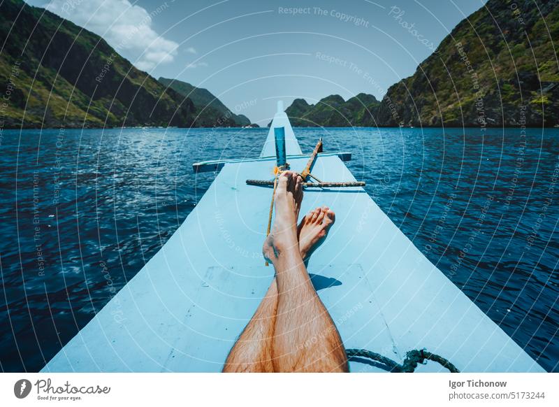 Legs of man on banca boat approaching tropical island. travel, relaxation and vacations concept freedom legs water day journey nature outdoors people sunlight