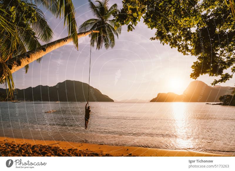 Silhouette of swing men with sunset over tropical island in background. El Nido bay. Philippines philippines man el nido seaview recreation bungee leisure male