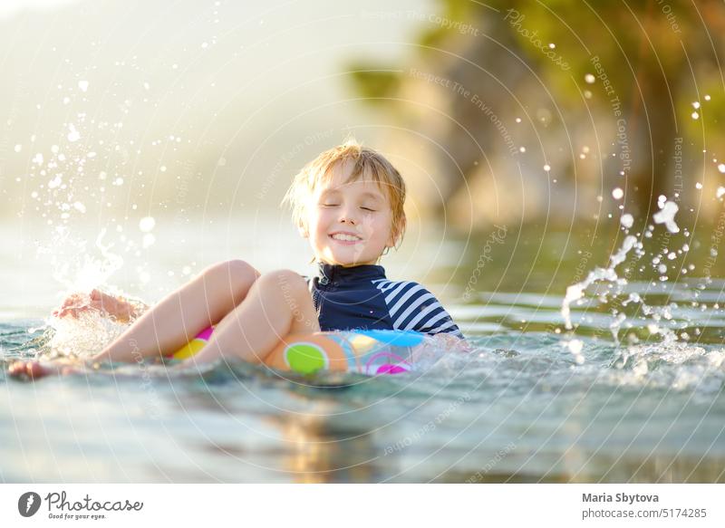 Little boy swimming with colorful floating ring in sea on sunny summer day. Cute child playing in clean water. Family and kids resort holiday during summer vacations.