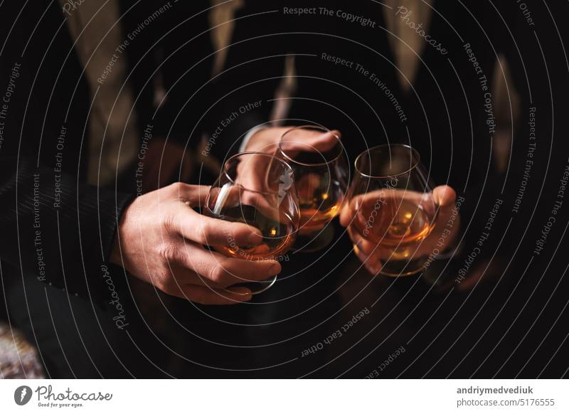 Business meeting. Men hold glasses of whiskey. Men's Party. Hand with a drink of alcohol party toasting whisky friends scottish men people background hand hands
