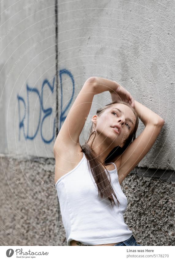Concrete and murals surround this gorgeous brunette girl with a white top. Looking splendidly in a casual fashion this pretty woman is feeling in love. Beauty in suburbs.
