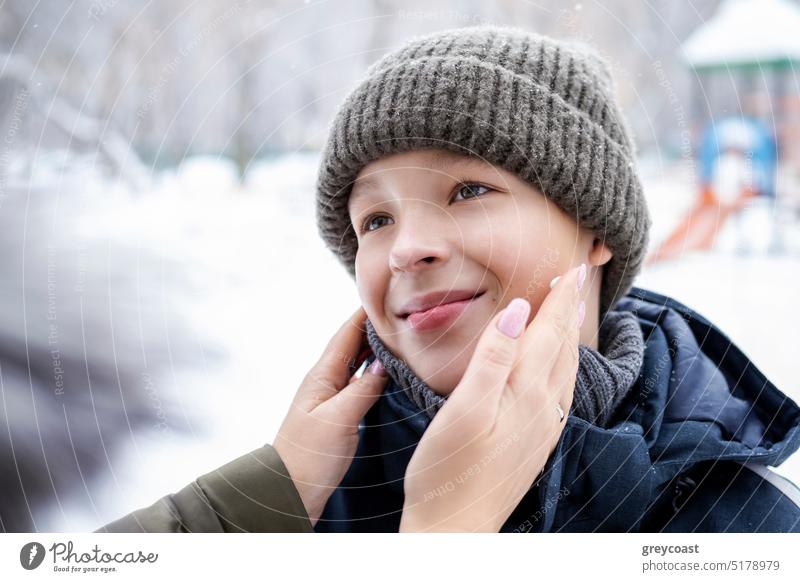 Mother applying cream to son face on winter day kid people boy take care skin dry child teen teenager lotion facial cold woman weather skincare cosmetics