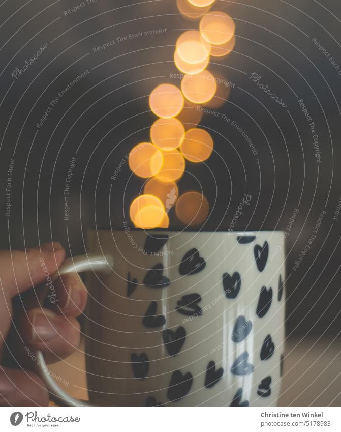 The points of light seem to float upwards like steam from a coffee mug Coffee mug Fairy lights bokeh lights Hand clearer blurriness Glittering defocused Light