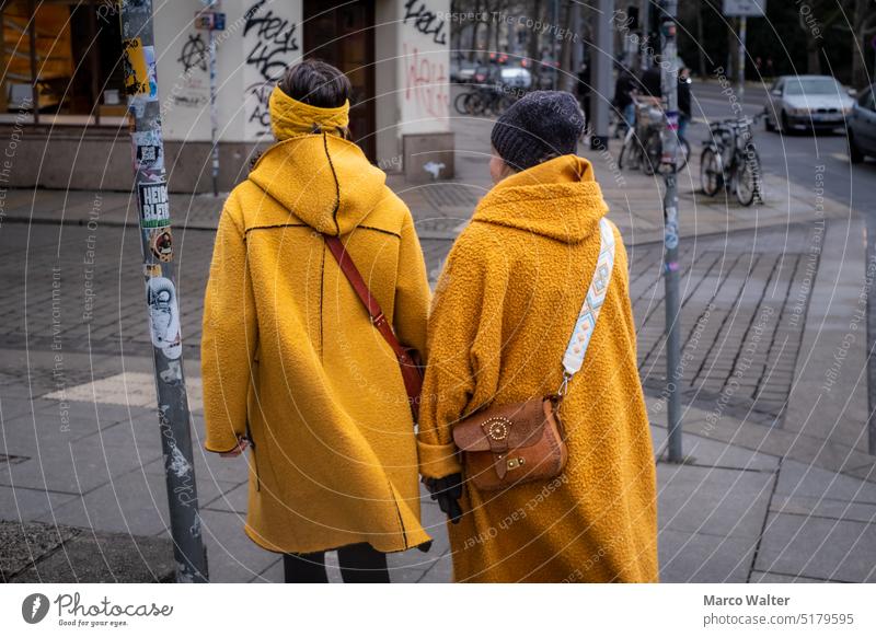 Two women in yellow jackets and bag. two Woman two persons people Outdoors Street Yellow Bag Cap Headband Footpath