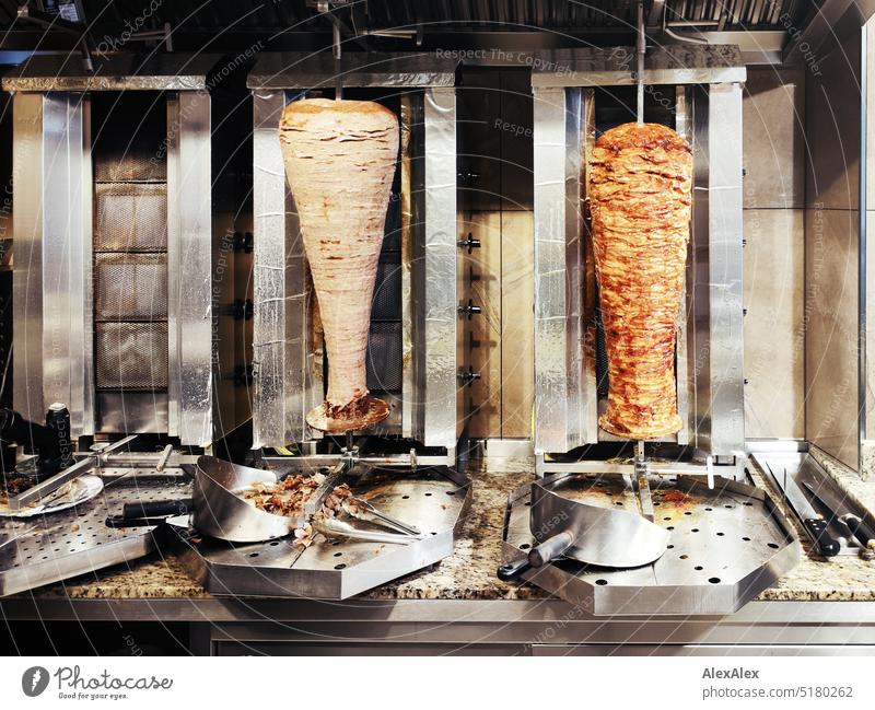 Two kebab skewers in front of three kebab grills in a snack bar Snack bar Eating Meat Veal Chicken meat Poultry eat out Outward Nutrition Barbecue (apparatus)