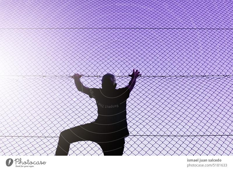 man climbing the metal fence one person silhouette metallic fence grabbing free freedom street alone loneliness outdoors bilbao spain