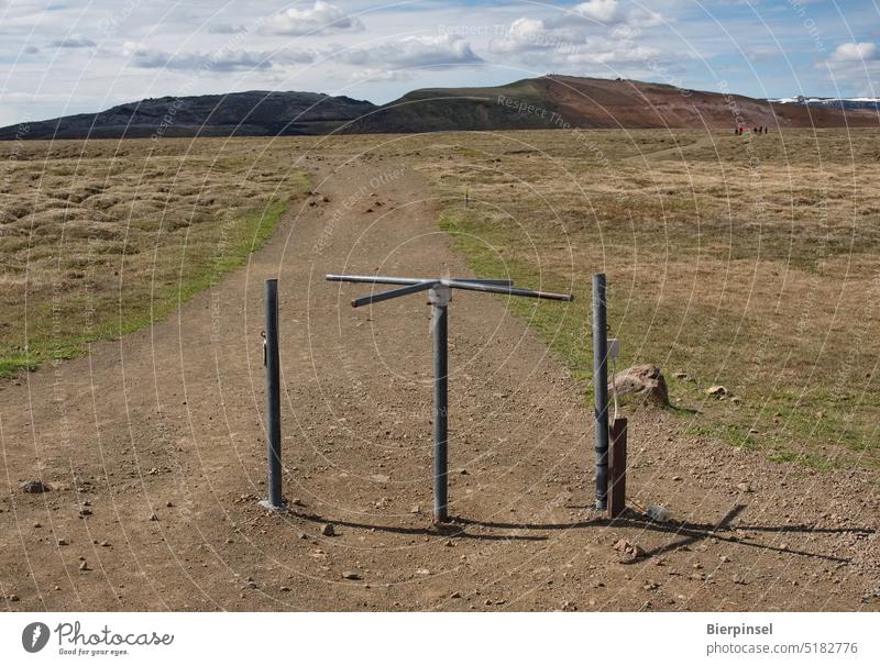 Functionless turnstile on a hiking trail in Iceland Metal Landscape treeless sunny mountain hiking area Tourism Krafla area Sky Clouds