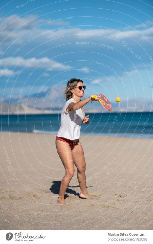 Pregnant woman playing beach tennis on the beach of Alicante in Spain. abdomen adult awaiting baby beautiful beauty belly birth care childbirth family female