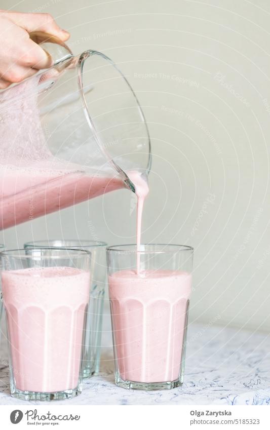 Strawberry milkshake pouring in glass. strawberry drink summer smoothie refresh recipe pink healthy eating food yogurt cold table white close up selective focus