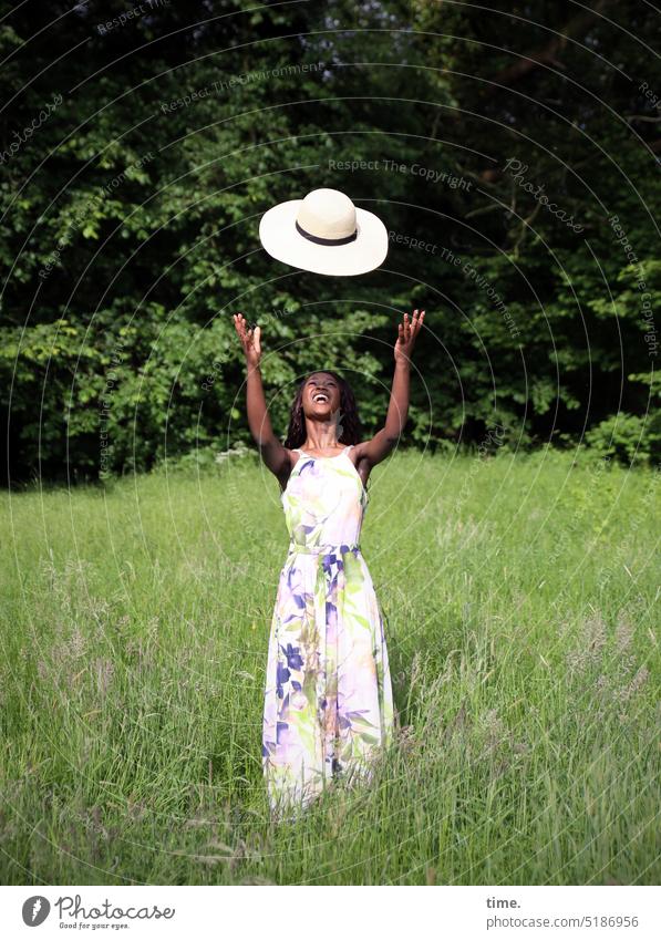 laughing woman with flying straw hat in a meadow Feminine Woman Park Meadow Dress Hat Long-haired Dark-haired Laughter Stand Joy Happy pretty Happiness Free