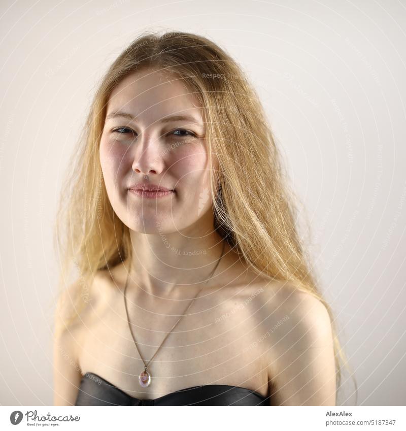Close portrait of young blonde woman standing in front of white background Fresh Looking into the camera Expectation inside Self-confident feminine Charming