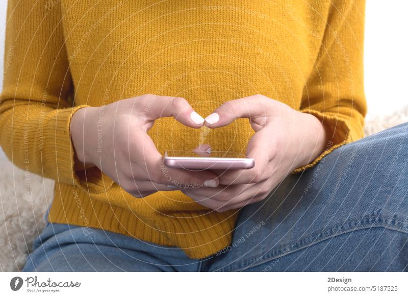 Close up of a woman's hands in yellow sweater using a mobile phone jersey typing closeup mustard person technology communication smartphone screen female