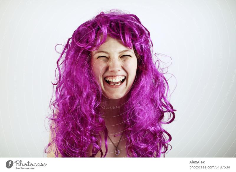 Close portrait of young blonde woman laughing against white background with purple hair Fresh Looking into the camera Expectation inside Self-confident feminine