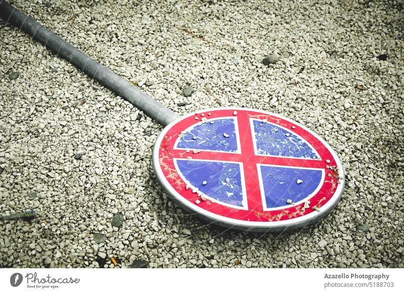 Red and blue prohibition signpost lying on the ground. Fallen road sign. parking fallen gravel stones minimalism object broken regulation pole icon symbol law