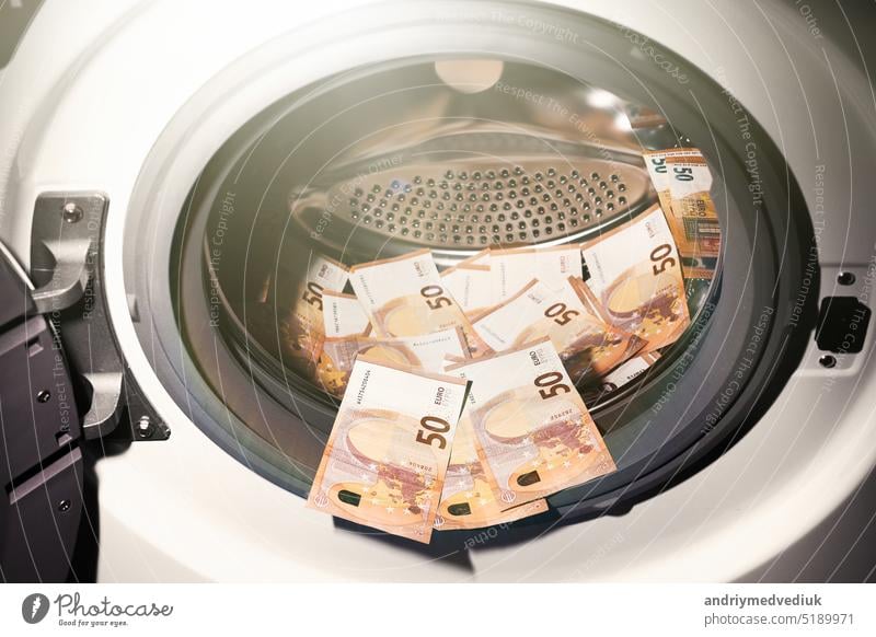 50 euro banknotes inside washing machine. Money laundering symbol. Tax evasion. Illegal financial transactions. Euro currency business laundry money economy