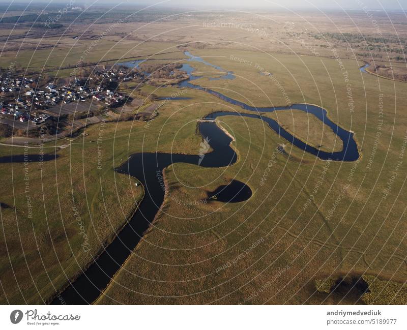 aerial view of a beautiful winding river flows among the fields, which flows picturesquely, creating incredible landscapes. between flooded fields and swamps.