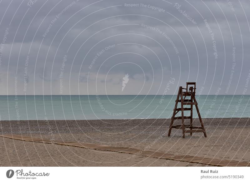 A wooden lifeguard chair on lonely beach flare help helpful horizon horizontal lens safety storm warm wave weather insure patrol saver windy danger empty