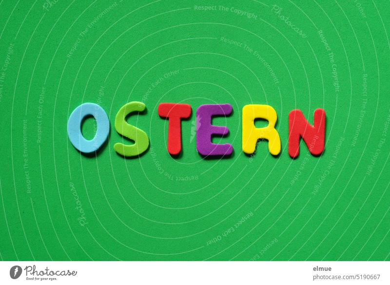 EASTER is written in colored letters on green background Easter Letters (alphabet) variegated Easter decoration abstraction illustration Easter card flatlay