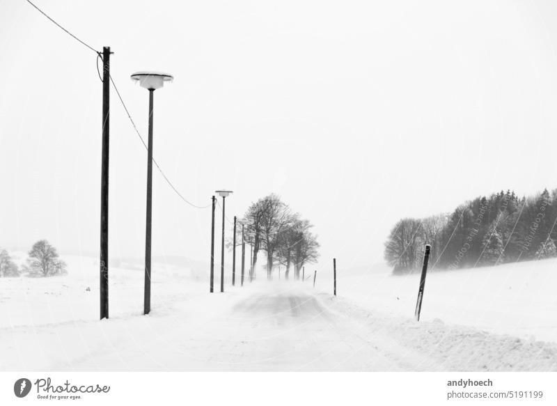 Snow covered country road downhill in the middle of Germany alone asphalt blizzard cold cold temperature concept direction exploration explorer forward freeze