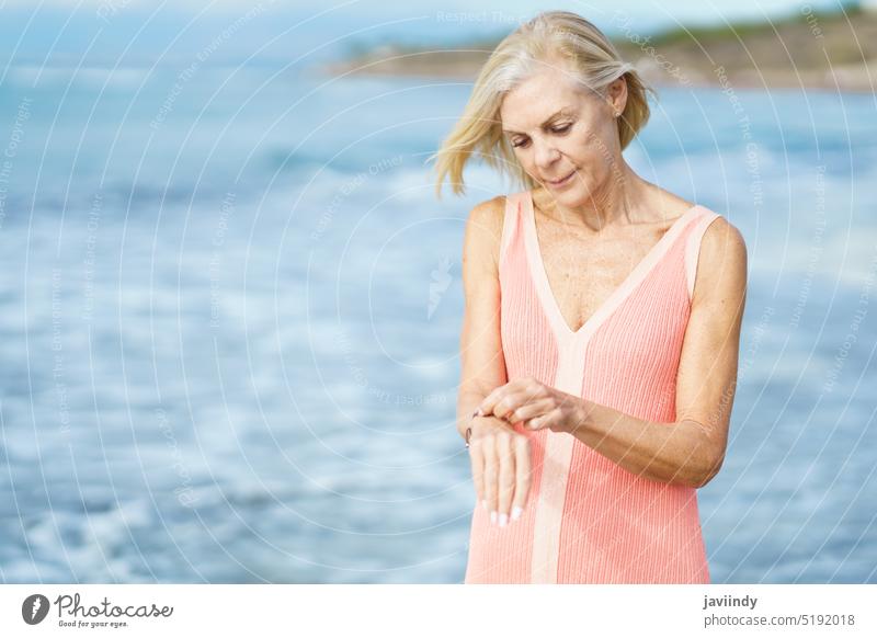 Mature woman on shore of a beach. Elderly female enjoying her retirement at a seaside retreat. mature senior old person lifestyle happy holiday relaxing sand