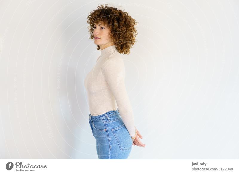 Emotionless woman standing with hands clasped behind back hand behind back slim studio shot calm curly hair posture short hair brown hair unemotional