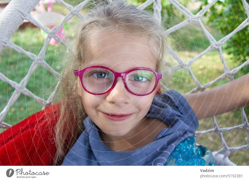 Happy funny girl in glasses close-up in nature Girl smile hair Caucasian horizontal happiness child hanging chair street summer adorable baby beautiful cheerful