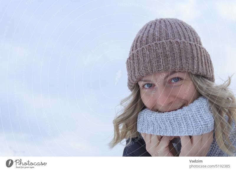Woman with blond hair in knitted cap and sweater smiling on light background closeup Face Smiling Hair Outdoors Winter Hat Knitted Sweater daylight Caucasian