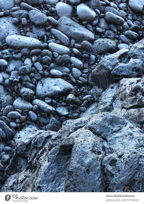 Black volcanic rocks texture. Stones of dark blue color background. Igneous rock formation backdrop. Rough natural textured vertical wallpaper. stone pattern