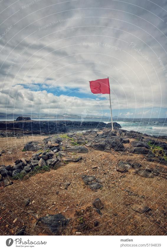 Red flag on the coast Sky Clouds Gale Rock Ocean Blue sky Landscape Colour photo Exterior shot Deserted