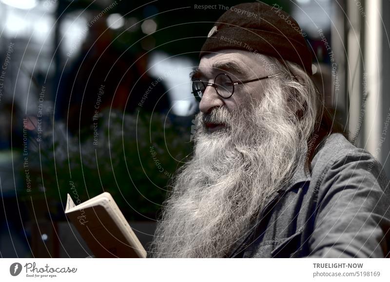 Old man, Tolstoy connoisseur and fan, with a mighty white razor beard, glasses and black cap sits in a sidewalk café in the evening and studies his notebook