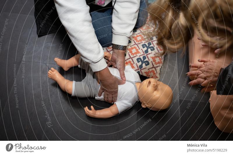 Three people practice first aid and CPR with an adult CPR manikin and another baby resuscitation manikin dummy course cpr cpr dummy medical baby mannequin