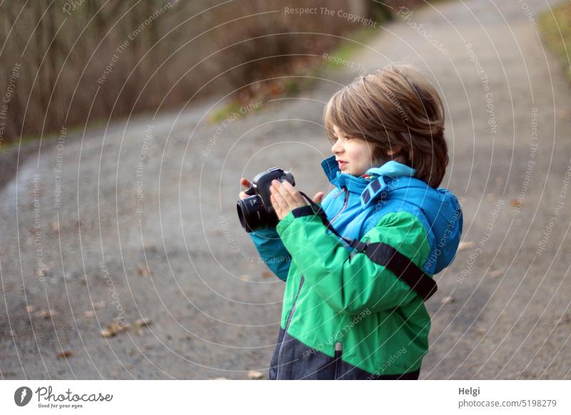 PC offspring - portrait of a boy holding a camera in his hand and smiling at the display Human being Child Boy (child) Take a photo look Smiling Stand snip